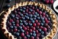 A pie adorned with assorted berries is placed upon a wooden table.