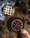 Pie with berries on a brown wooden table made of planks, top view. Children`s hands in the frame take a knife to cut the pie. Spri Royalty Free Stock Photo