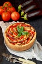Pie with eggplants, tomatoes and cheese on the gray plate decorated with fresh basil leaves and vintage forks. Homemade tart Royalty Free Stock Photo