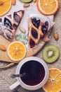 Pie with jam from berries with a cup of tea, dried oranges, kiwi slices and nuts. Delicious pie on a wooden table. Royalty Free Stock Photo