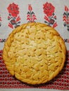 Pie with a pattern of dough on an embroidered towel.