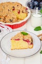 Pie with plums and shtreisel on a plate on a white wooden background. Royalty Free Stock Photo