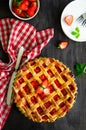 Pie with rhubarb and strawberries on a dark wooden background with fresh strawberries. Vertical orientation, copy space