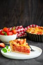 Pie with rhubarb and strawberries on a dark wooden background with fresh strawberries. Vertical orientation, copy space