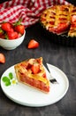 Pie with rhubarb and strawberries on a dark wooden background with fresh strawberries. Vertical orientation, copy space