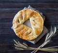 Pie with sesame on a sacking and ears of wheat. Dark wooden background Royalty Free Stock Photo