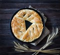 Pie with sesame on a sacking and ears of wheat. Dark wooden background Royalty Free Stock Photo