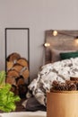 Pie of wood in metal stand next to king size bed with wooden headboard Royalty Free Stock Photo