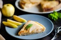 Piece of apple French pie on blue plate looks appetizing and surprisingly fresh. Thin slices of juicy apples and crispy puff Royalty Free Stock Photo