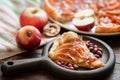 A piece of apple pie with roasted peanuts, fresh apple and caramel sauce on a plate