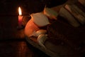 a piece of bacon, onion, garlic, black bread on a wooden table in the dark next to a burning candle, candlelight dinner