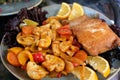 A piece of baked trout with mushrooms and vegetables on a plate with lemon slices.