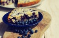 Piece of bilberry pie on a blue plate and juicy berries of bilberry