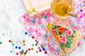 Piece of birthday cake, tea in cup, gift box and colorful confetti Royalty Free Stock Photo
