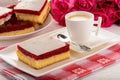 Piece of biscuit cake with cream and cherry jelly and cup of coffee. Royalty Free Stock Photo