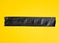 piece of black tape tape on yellow background.