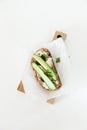 A piece of bread with butter, salt with cucumber and greens lies on a wooden board on a white background.