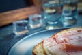 A piece of bread with slice of pork and shots of vodka on wooden background Royalty Free Stock Photo