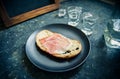 A piece of bread with slice of pork and shots of vodka on wooden background Royalty Free Stock Photo