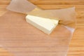 Piece of butter in waxed paper on a wooden surface