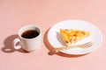 Piece of cake on white plate with fork next to cup of tea on pink background Royalty Free Stock Photo