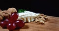 A piece of camembert cheese with nuts and grapes lie on a wooden board. Camembert cheese with white noble mold Royalty Free Stock Photo