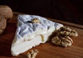 A piece of camembert cheese and walnut lie on a wooden board. Camembert cheese with white noble mold Royalty Free Stock Photo