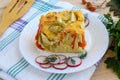 A piece of casserole of vegetables (zucchini, carrots) on a white plate.