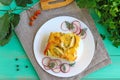 A piece of casserole of vegetables (zucchini, carrots) on a white plate.