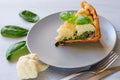 A piece of cauliflower pie on the gray plate decorated with fresh basil leaves and vintage silver knife and fork Royalty Free Stock Photo