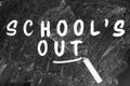 Piece of chalk and text SCHOOL`S OUT written on blackboard Royalty Free Stock Photo