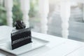 A piece of charcoal cake on white wooden table.