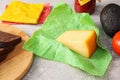 Piece of cheese in beeswax food wrap on light grey table