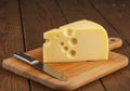 Delicious Block of Swiss Cheese Slice with Natural Holes on Wooden Cutting Board with Knife Royalty Free Stock Photo