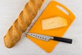 Piece of cheese, knife on cutting board, loaf of bread Royalty Free Stock Photo