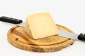 Piece of cheese on wooden board with knife