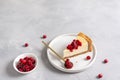 A piece of cheesecake with cranberry sauce on white plate on gray background. Copy space. Confectionery, bakery, menu, recipe