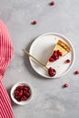 A piece of cheesecake with cranberry sauce on white plate on gray background. Top view. Confectionery, bakery, menu, recipe