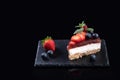 Piece of cheesecake served on slate plate isolated on black background with copyspace. Homemade bakery concept