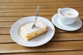 Piece of cheesecake with tangerines and icing sugar, a cake fork and a cup of coffee on a wooden table in the cafe, copy space, Royalty Free Stock Photo