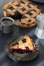 A piece of cherry pie lies on a ceramic plate and a cup of coffee with milk jug stand on the table Royalty Free Stock Photo
