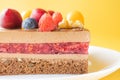 A piece of chocolate berry cake in a white plate on a yellow background. Royalty Free Stock Photo