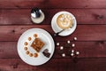 A piece of chocolate brownie and caramel sauce, a cup of cappuccino on a white plate. Top view Royalty Free Stock Photo
