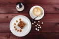 A piece of chocolate brownie and caramel sauce, a cup of cappuccino on a white plate. Top view Royalty Free Stock Photo