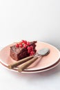 A piece of chocolate cake brownie decorated with red currant berries on pink plate white marble table, copy space Royalty Free Stock Photo
