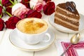 Piece of chocolate cake, cappuccino, flowers on table