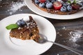 Piece of chocolate cake with fresh blueberries and mint on a white saucer on a dark wooden , dessert Royalty Free Stock Photo