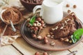 Piece of chocolate cake, mint leaves, hazelnuts and jar with milk Royalty Free Stock Photo