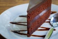 Piece of chocolate cake with spoon on white plate