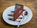 Piece of chocolate cake with spoon on white plate